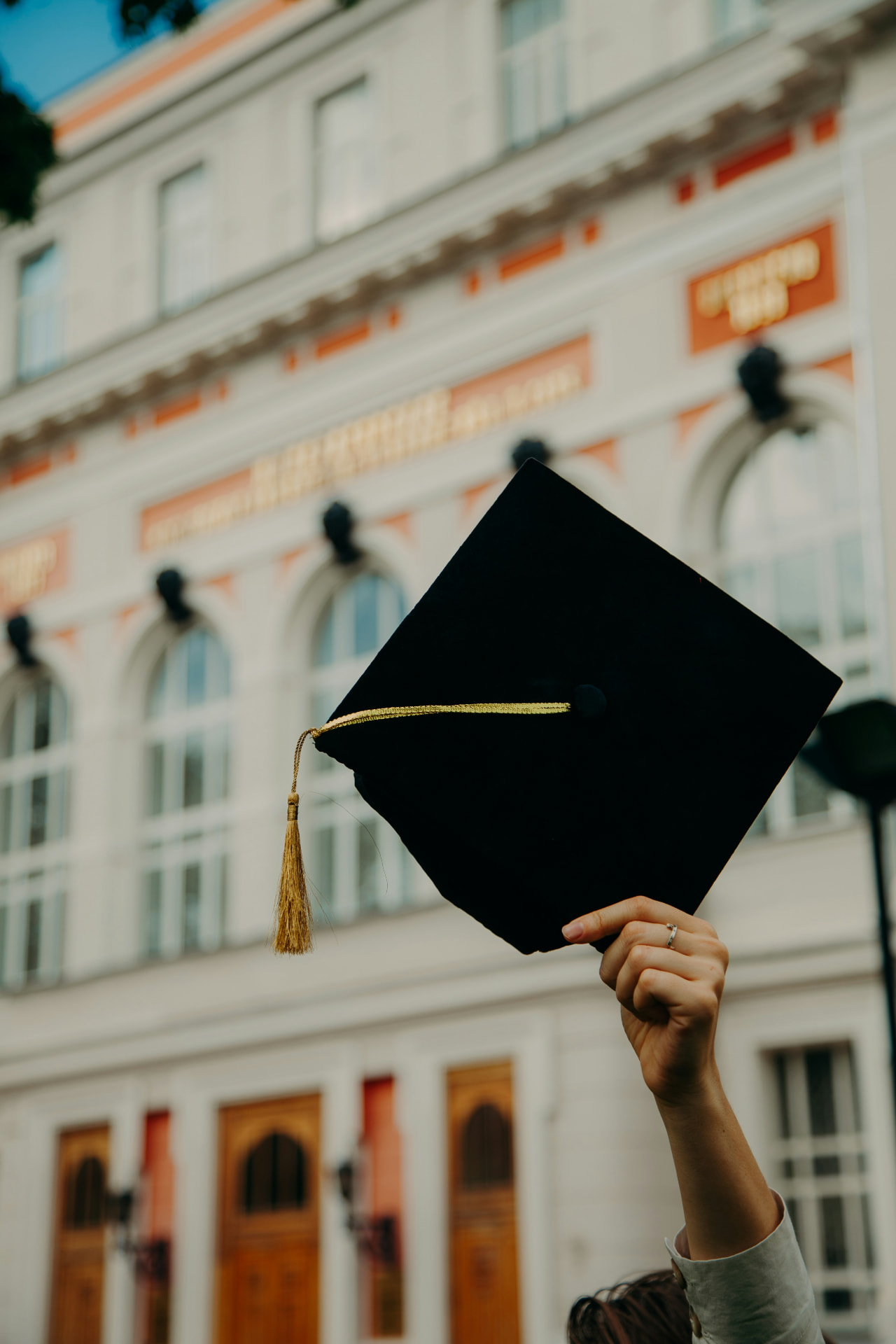 A graduate holding up a graduation cap